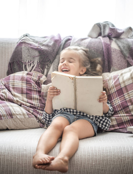 ソファで本を読む少女 - 写真・画像