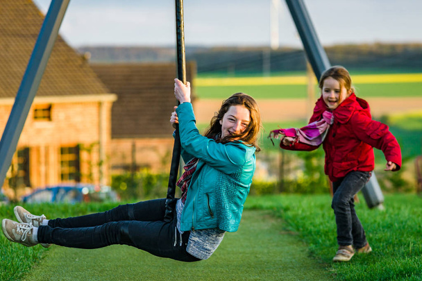 Deux sœurs : maternelle et adolescente - jouer sur une aire de jeux
 - Photo, image