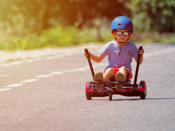 Joyeux garçon debout sur hoverboard ou gyroscooter avec kit accessoire kart en plein air. Nouvelles technologies modernes
 - Photo, image