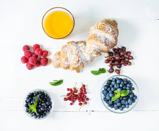 Croissant with fresh berry and juice for breakfast. - Фото, зображення