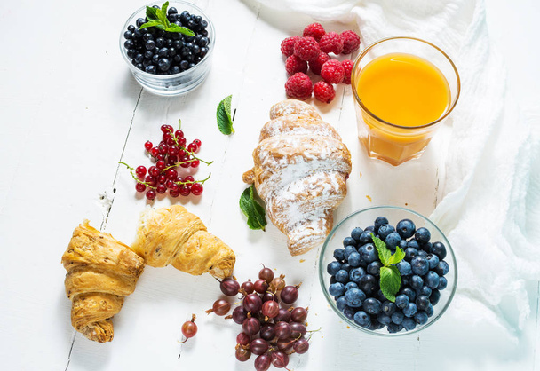 新鮮なベリーと朝食のためのジュースとクロワッサン - 写真・画像