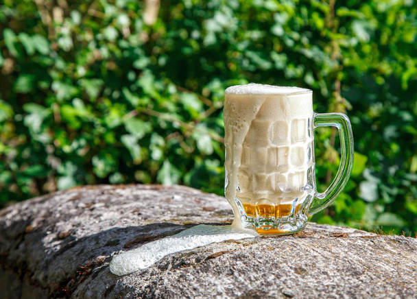 γυάλινη κούπα με μπύρα στέκεται στην μεγάλη πέτρα - Φωτογραφία, εικόνα