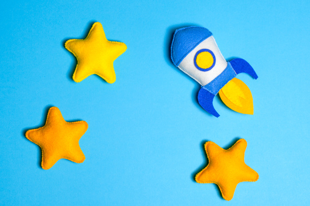 Rocket takes off. Hand made felt toys. Space ship with yellow stars on blue background. - Foto, afbeelding