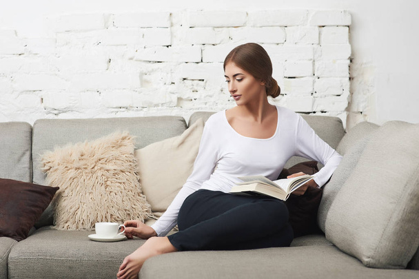 Woman reading a book on sofa - Фото, зображення