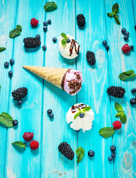 gombóc fagylalt a friss bogyós gyümölcsök a kék fa háttér - Fotó, kép