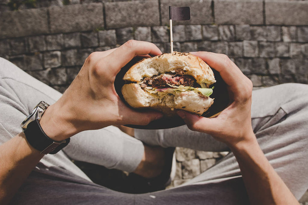 Man eating fresh tasty grilled burger. Top view - 写真・画像
