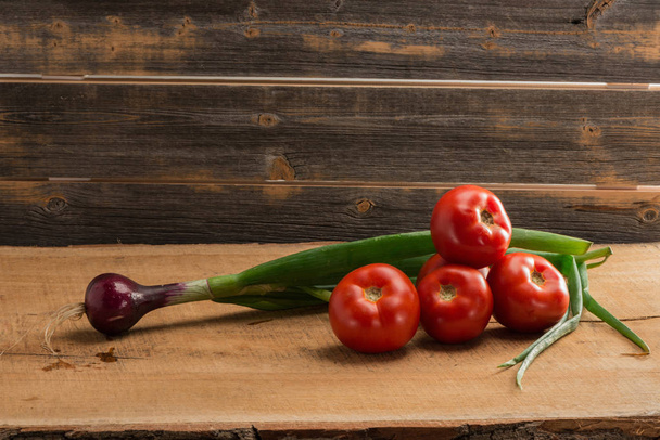 Green onions and tomatoes against the background of old boards - Foto, Imagen