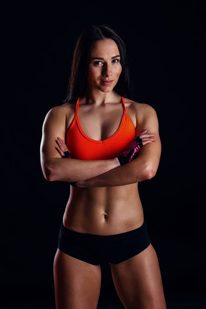 Beautiful fitness sexy slim female in activewear posing over black background. - Foto, Bild