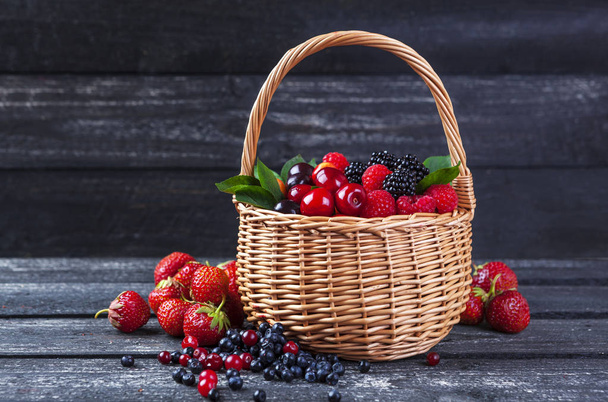 Berries mix in basket on dark wooden background - Fotoğraf, Görsel