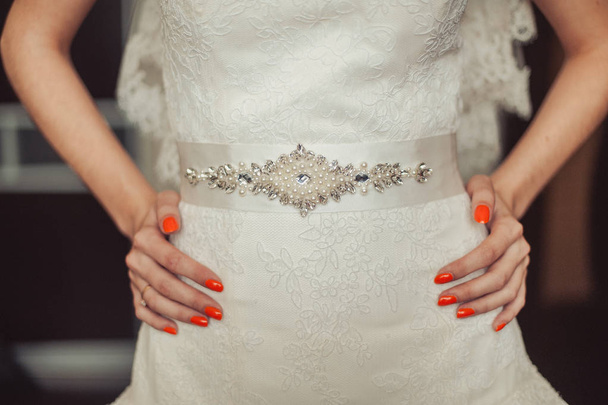 Manos de la novia con manicura naranja en el vestido
 - Foto, imagen