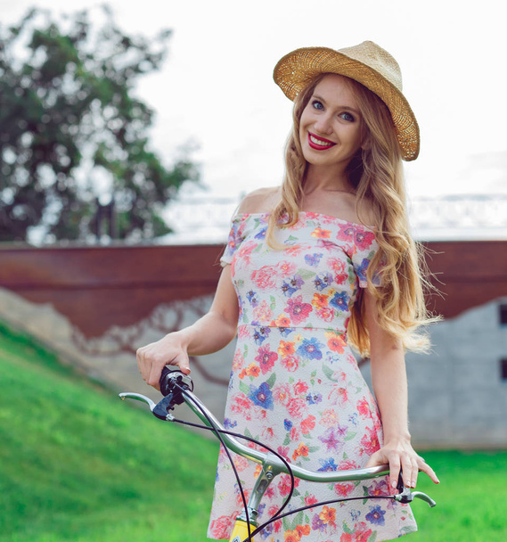 Portrait of beautiful blonde girl riding bike in park - Photo, image