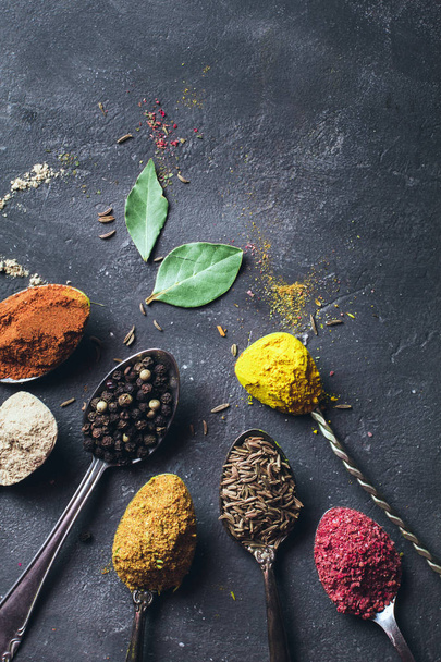 Beautiful colored spices in a silver spoon on a dark background. The concept of cooking, healthy food - Fotografie, Obrázek