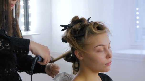 Profesionální kadeřník dělá účes pro ženu - jejich kadeře - Záběry, video