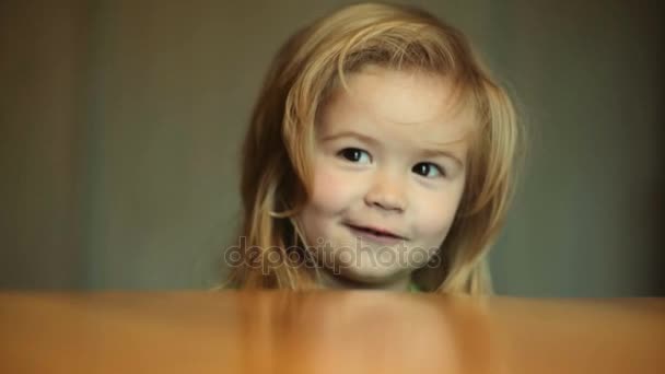 SMIL gyermek konyha, mosolyogva aranyos baba az asztalnál. Kisgyerek is boldog és mosolyog, otthon a konyhában. Portré fiú fogak és gyönyörű haj. Kisgyermek zöld póló beszél - Felvétel, videó