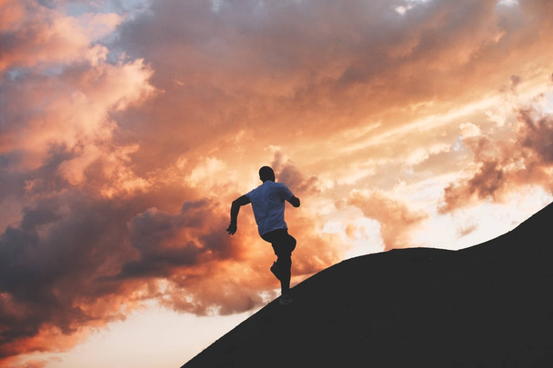 Чоловік спортсмен біжить навколо пагорбів на заході сонця. Спортивні поїзди в природі
 - Фото, зображення