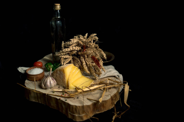 Kraft zelfgemaakte kaas op de donkere achtergrond met groenten met flessen op houten tafel - Foto, afbeelding
