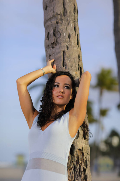 Woman leaning on a palm tree - Photo, Image