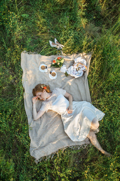 Mulher atraente desfrutando de piquenique romântico ao pôr do sol no campo
 - Foto, Imagem