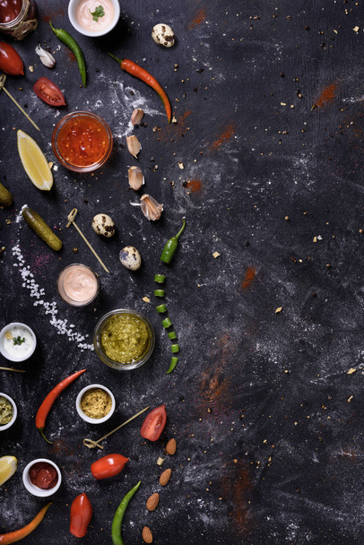 Variety of sauces, ingredients and snacks on dark messy table.  - Zdjęcie, obraz