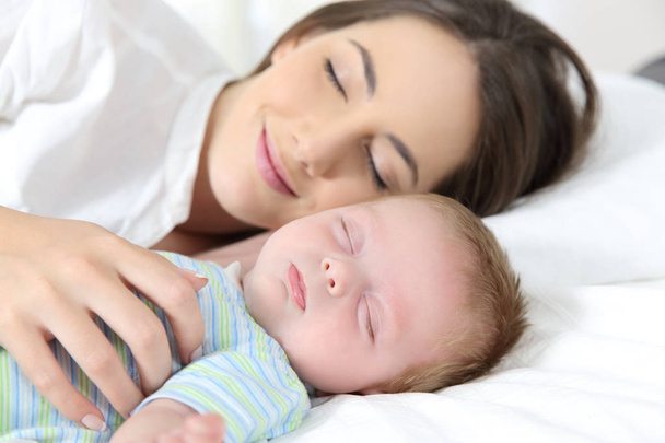 Moeder en baby slapen samen op bed - Foto, afbeelding
