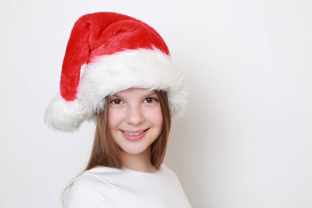 Teen girl in Santa hat posing on camera - Foto, afbeelding