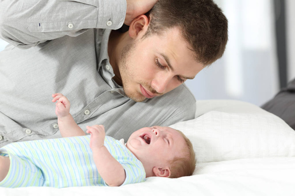 Pai confuso e seu filho bebê chorando
 - Foto, Imagem