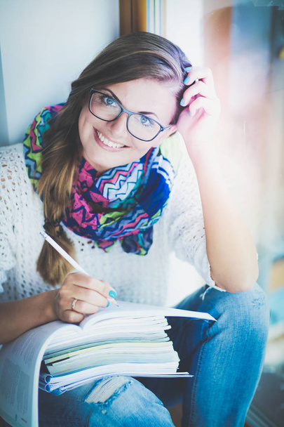 Young woman sitting at a desk among books. Student - Foto, Imagen
