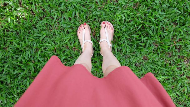  Close Up on Girl's Feet Wearing Sandals on Green Grass - Photo, image