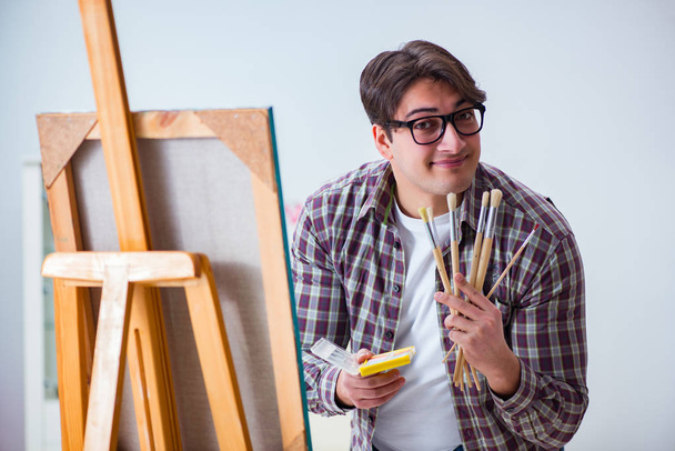 Junger männlicher Künstler zeichnet Bilder im hellen Atelier - Foto, Bild