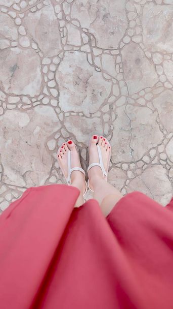 Close Up on Girl's Feet Wearing Sandals and Red Nail on The Tile - Photo, image