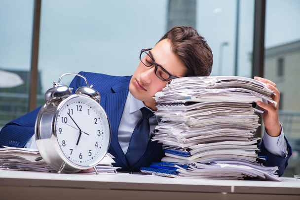 Businessman with pile stack of paper paperwork and an alarm cloc - Photo, Image