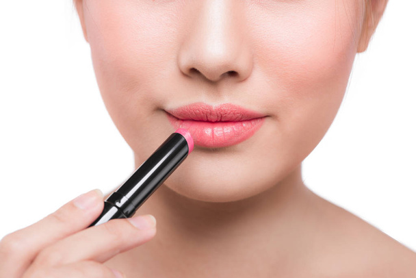 Vrouw die roze lippenstift aanbrengt - Foto, afbeelding