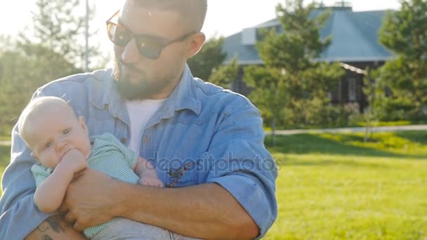 Szczęśliwy ojciec trzymający syna na zachodzie słońca - Materiał filmowy, wideo