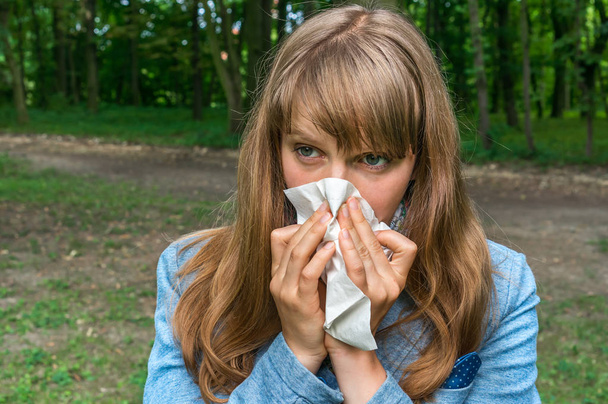 Woman with flu or allergy symptoms in park - Photo, Image