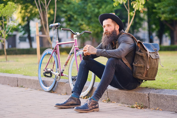 Hipster sits on a step and using a smartphone - Fotografie, Obrázek