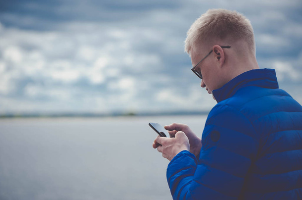Sarışın adam cep telefonuyla gölde - Fotoğraf, Görsel