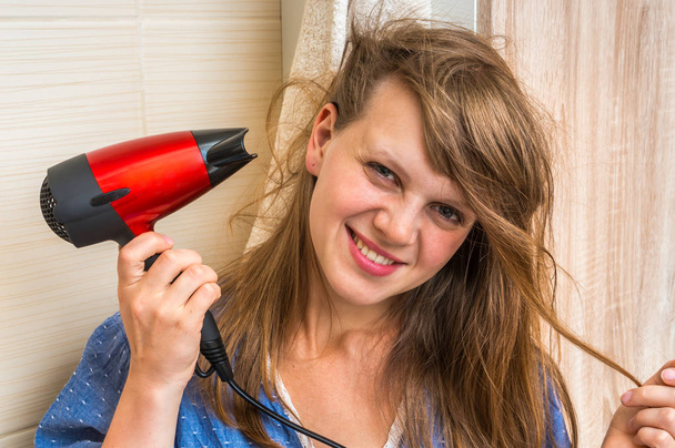 Beautiful young woman dries hair with hair dryer - Photo, Image