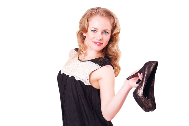 Young cheerful woman in a black short dress and high heels in her hands. - Photo, image