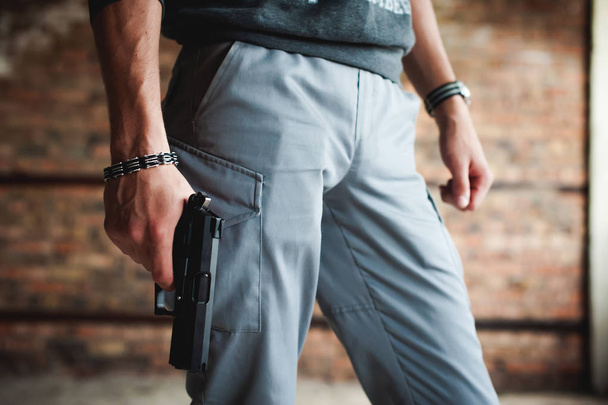 athletic man holding a gun in his hand on the ready - Photo, image