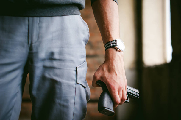 Dangerous athletic man, holds a gun in his hands, close-up. Wristband and watch - Foto, immagini