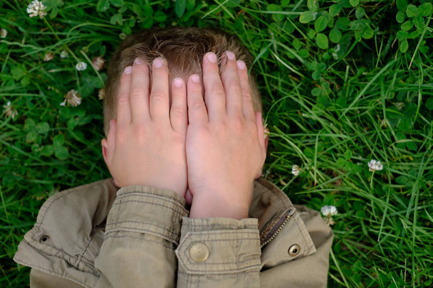 Teenage boy closes his eyes with hands - Foto, Bild