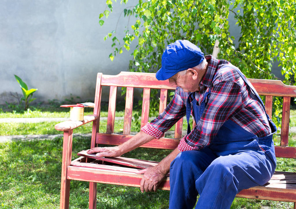 Old man repairing bench in garden - Zdjęcie, obraz