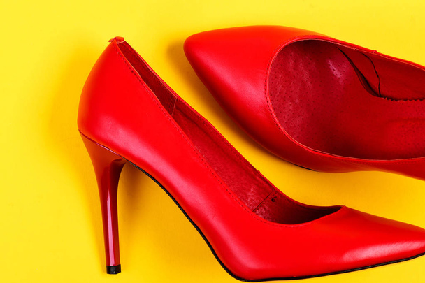 Elegant female shoes in red color on juicy yellow background - 写真・画像