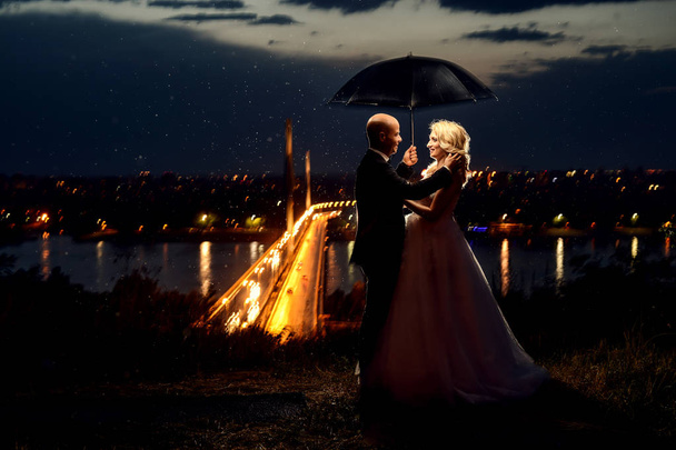 Recién casada pareja de pie bajo el paraguas
 - Foto, imagen