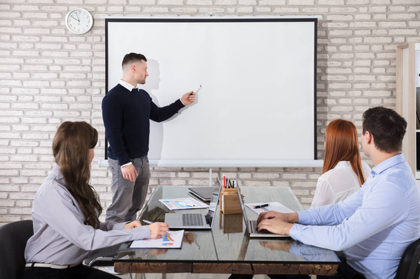 Businessman Giving Presentation To His Colleagues In Business Meeting - Photo, Image