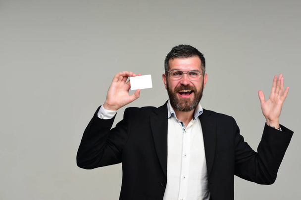 Man in suit with beard holds white business card - 写真・画像