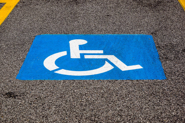 Vammaistunnus maalattu lattialle parkkipaikalla
 - Valokuva, kuva
