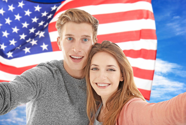 Young couple tacking selfie and USA flag on background - Фото, изображение