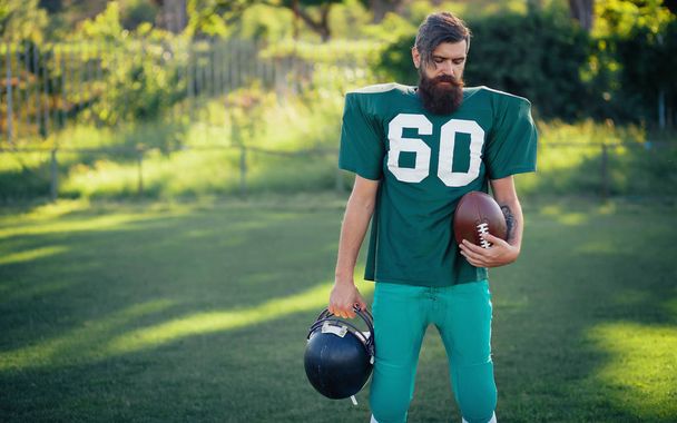 Jugador de fútbol americano con uniformes deportivos verdes con barba larga negra entrena en el campo de fútbol
 - Foto, Imagen