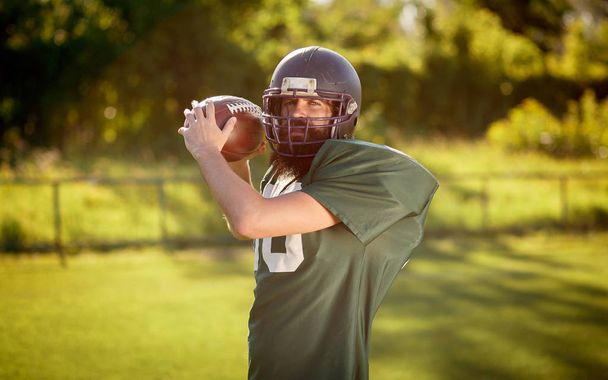 Jugador de fútbol americano con uniformes deportivos verdes con barba larga negra entrena en el campo de fútbol
 - Foto, Imagen